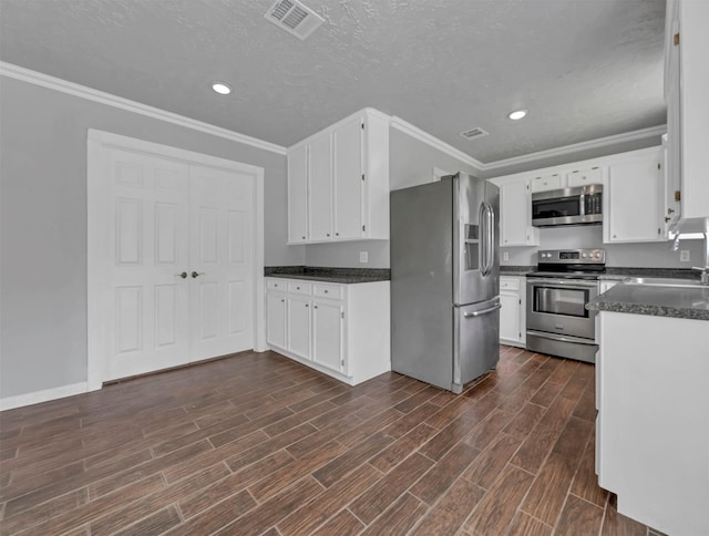 kitchen with visible vents, wood tiled floor, a sink, ornamental molding, and stainless steel appliances