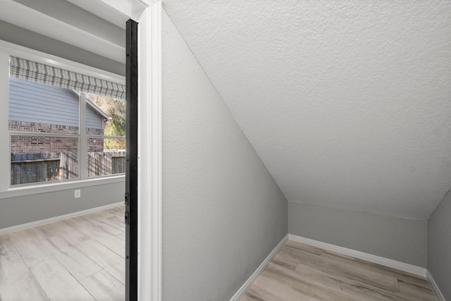 bonus room with baseboards, lofted ceiling, and wood finished floors