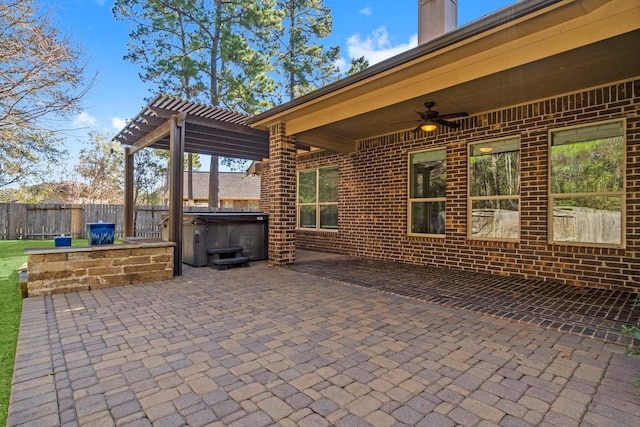 view of patio with a hot tub, ceiling fan, a pergola, and fence