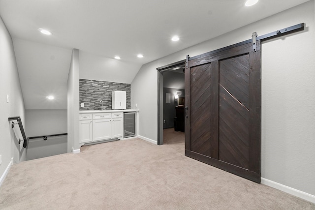 kitchen with tasteful backsplash, beverage cooler, a barn door, light carpet, and white cabinets