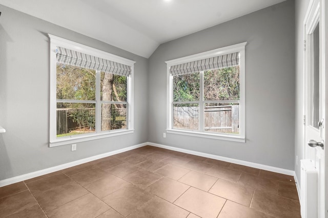 unfurnished room with dark tile patterned flooring, baseboards, and vaulted ceiling