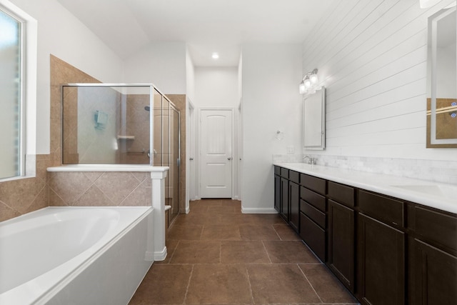 bathroom featuring a bath, a shower stall, double vanity, and a sink