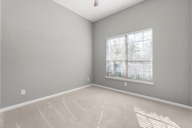 spare room featuring baseboards, light colored carpet, and a ceiling fan