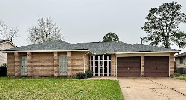 single story home with a front lawn, central AC, roof with shingles, concrete driveway, and a garage