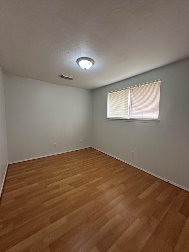 unfurnished room with visible vents, baseboards, light wood-style floors, and a textured ceiling