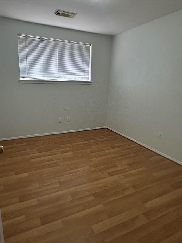 spare room with wood finished floors and visible vents