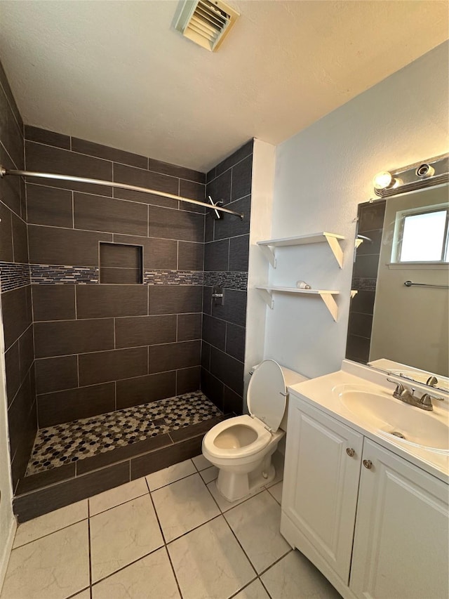 full bathroom featuring a tile shower, visible vents, and vanity