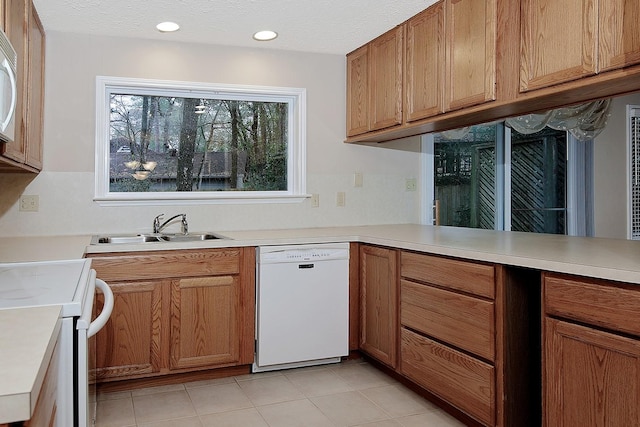 kitchen featuring a sink, white appliances, a textured ceiling, and light countertops