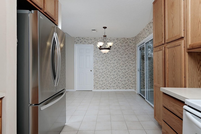 kitchen featuring visible vents, wallpapered walls, baseboards, light countertops, and freestanding refrigerator