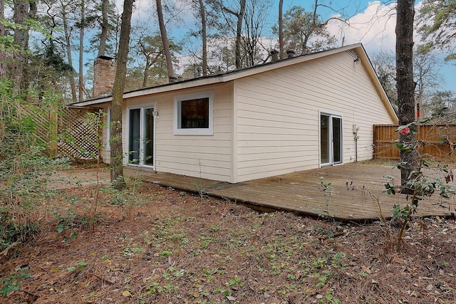 exterior space featuring a wooden deck, fence, and a chimney