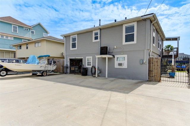 rear view of house with a gate, fence, and driveway