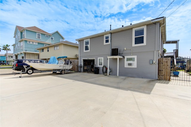 rear view of house featuring a gate, concrete driveway, a garage, and fence