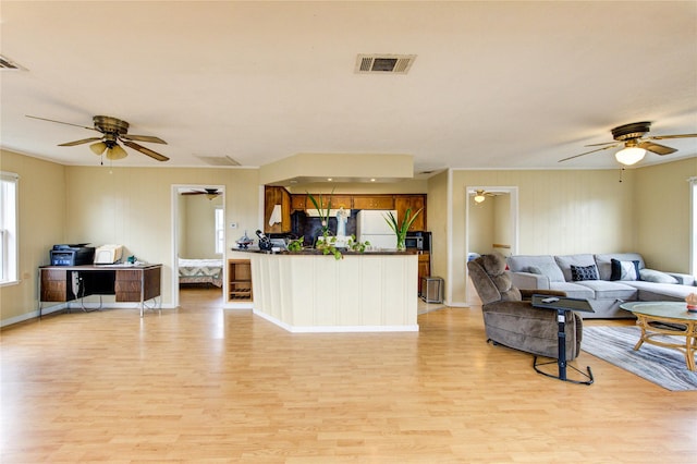 living area featuring light wood-style flooring, baseboards, visible vents, and ceiling fan