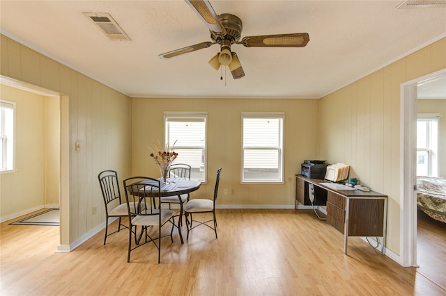 dining space featuring visible vents, crown molding, baseboards, ceiling fan, and light wood-style flooring