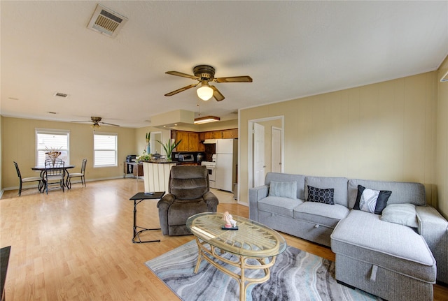 living room featuring visible vents, baseboards, light wood-type flooring, and a ceiling fan