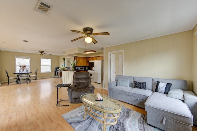 living room featuring light wood-style flooring, baseboards, visible vents, and ceiling fan