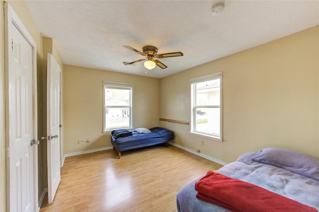 bedroom featuring light wood-style flooring, multiple windows, and baseboards