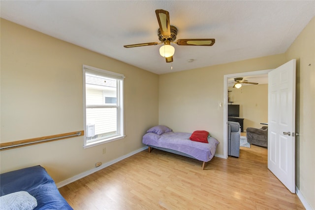 bedroom with light wood finished floors, ceiling fan, and baseboards