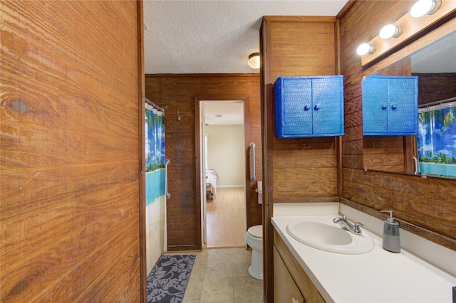 bathroom with a shower with curtain, toilet, a textured ceiling, wood walls, and vanity