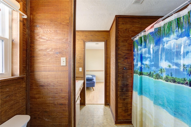 bathroom featuring toilet, curtained shower, a textured ceiling, wooden walls, and tile patterned flooring