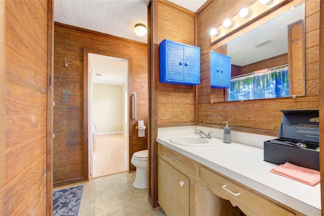 full bathroom featuring vanity, tile patterned floors, wooden walls, and toilet