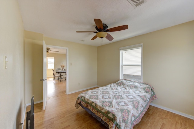 bedroom featuring light wood finished floors, visible vents, and baseboards