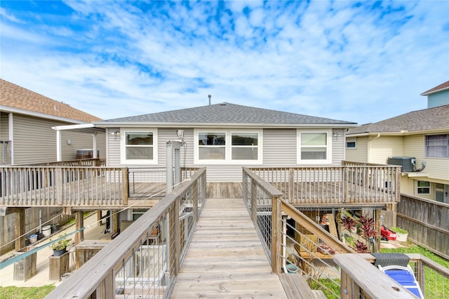 rear view of property with central air condition unit, a wooden deck, and a shingled roof