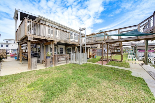 rear view of property featuring stairway, a patio, a lawn, and a wooden deck