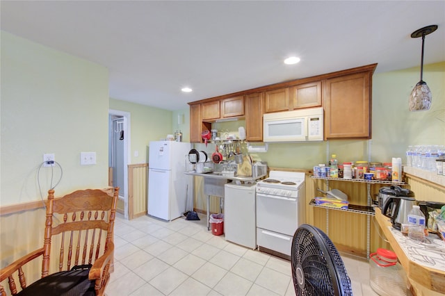 kitchen with light countertops, light tile patterned floors, brown cabinets, hanging light fixtures, and white appliances