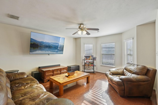 living room featuring visible vents, baseboards, ceiling fan, and wood finished floors