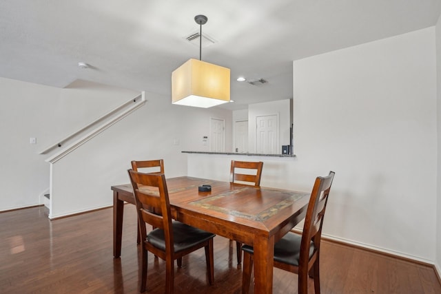 dining space with visible vents, baseboards, wood finished floors, and stairway