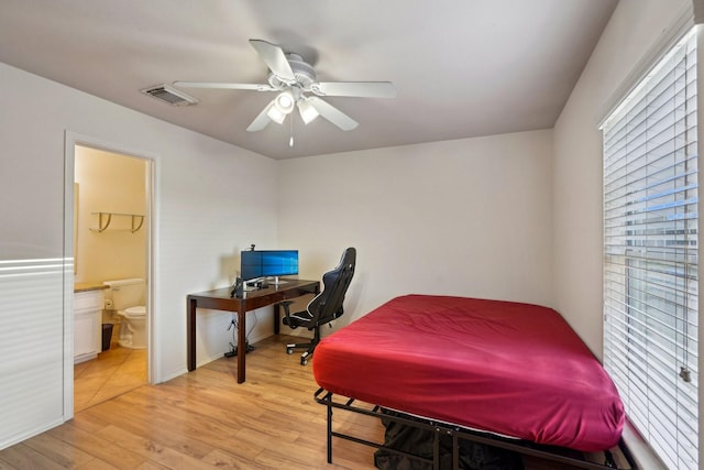 bedroom with light wood finished floors, visible vents, ensuite bathroom, and ceiling fan