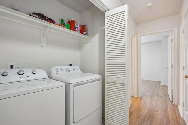 clothes washing area with independent washer and dryer, light wood-style flooring, and laundry area