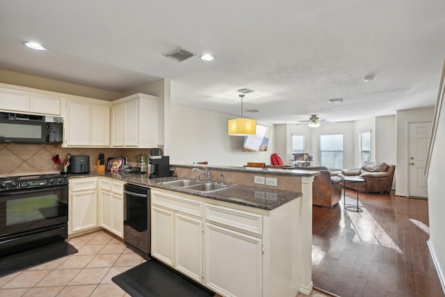 kitchen featuring tasteful backsplash, open floor plan, a peninsula, black appliances, and a sink