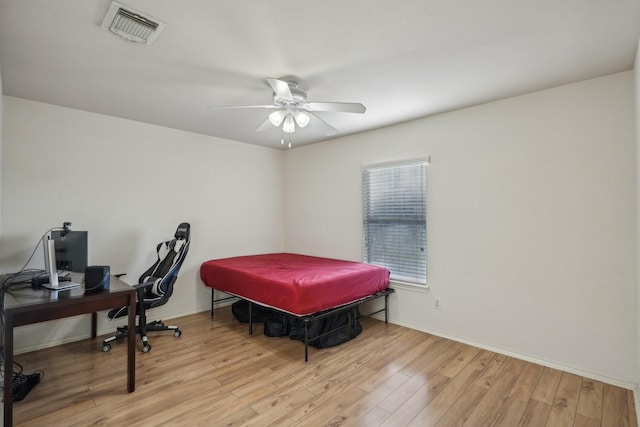 bedroom with ceiling fan, visible vents, baseboards, and wood finished floors