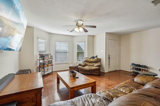 living room featuring a ceiling fan, wood finished floors, visible vents, and baseboards