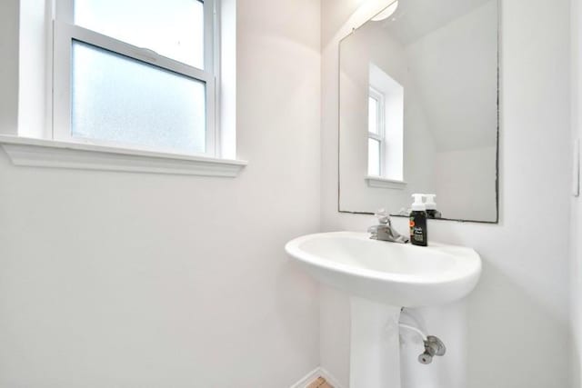 bathroom featuring a sink, baseboards, and vaulted ceiling