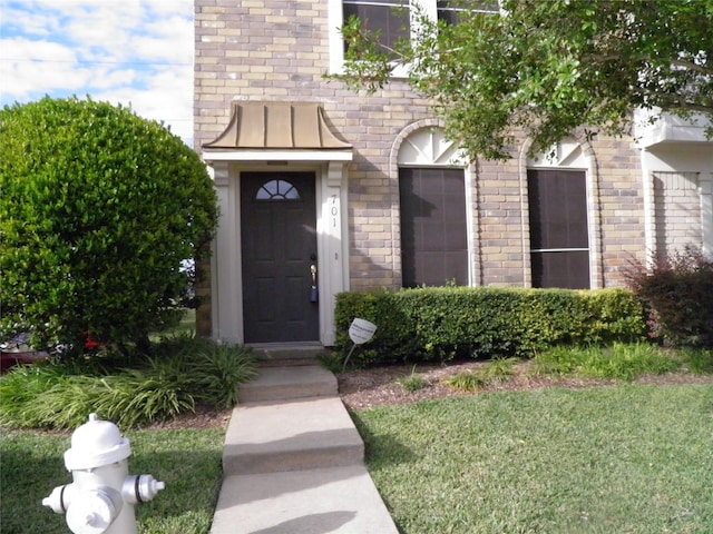 view of exterior entry featuring brick siding