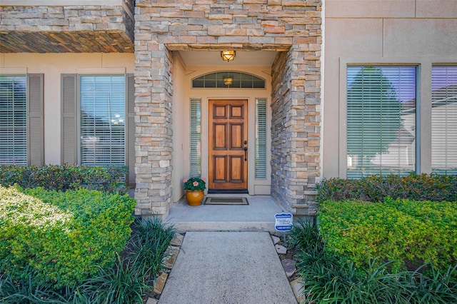 doorway to property featuring stone siding and stucco siding