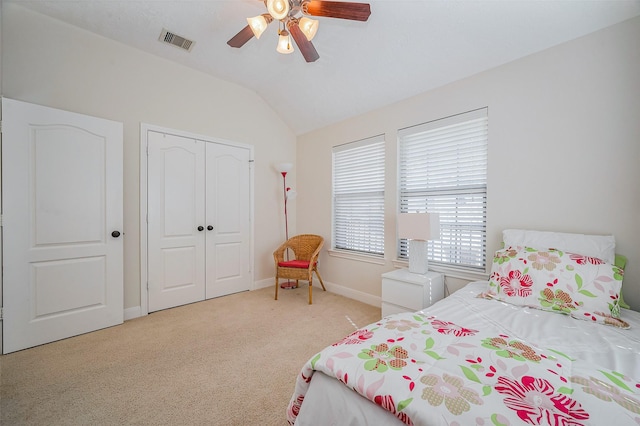 bedroom featuring visible vents, baseboards, light colored carpet, lofted ceiling, and a closet