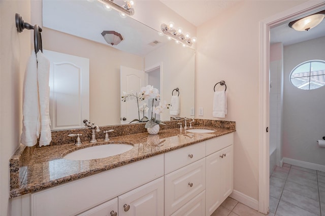 full bath with a sink, baseboards, double vanity, and tile patterned flooring