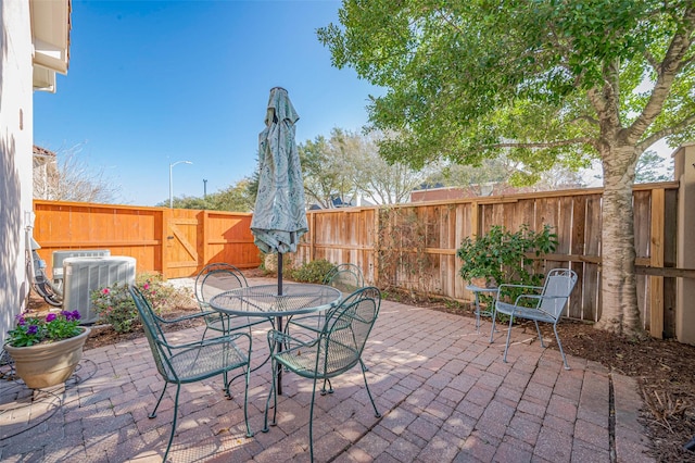 view of patio with central air condition unit, outdoor dining area, and a fenced backyard