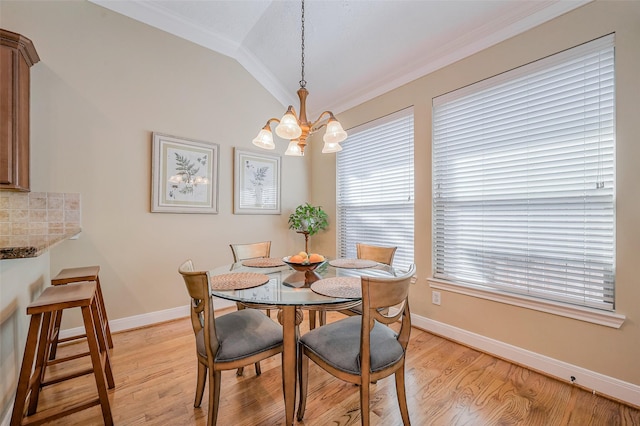 dining room with vaulted ceiling, a notable chandelier, crown molding, and light wood-type flooring