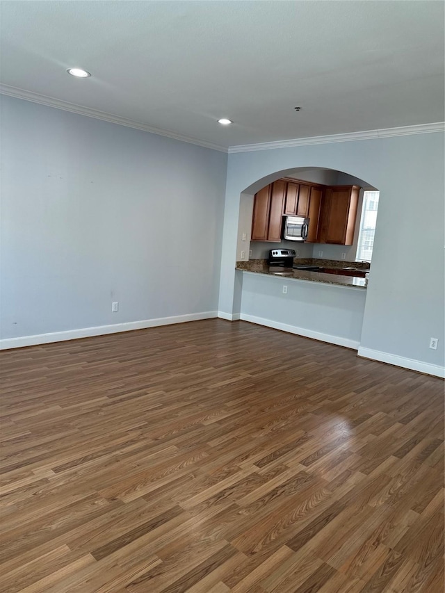 unfurnished living room with dark wood-type flooring, ornamental molding, recessed lighting, arched walkways, and baseboards