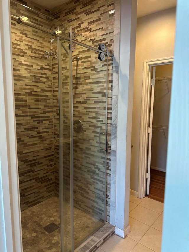 bathroom with tile patterned floors, a walk in closet, and a shower stall