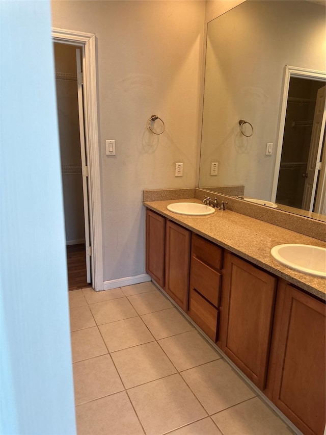 bathroom with a sink, a walk in closet, double vanity, and tile patterned flooring