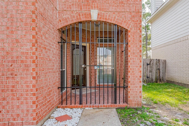 entrance to property featuring brick siding and fence