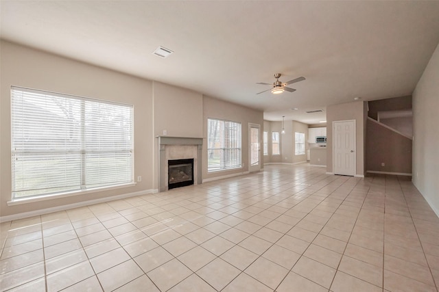 unfurnished living room featuring light tile patterned floors, a ceiling fan, visible vents, baseboards, and a tiled fireplace