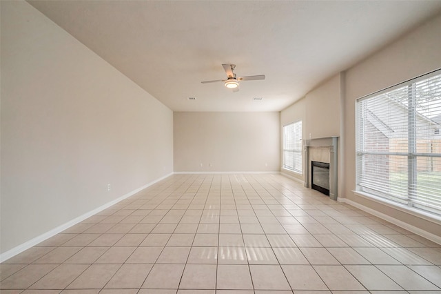 unfurnished living room featuring visible vents, a ceiling fan, a glass covered fireplace, light tile patterned floors, and baseboards