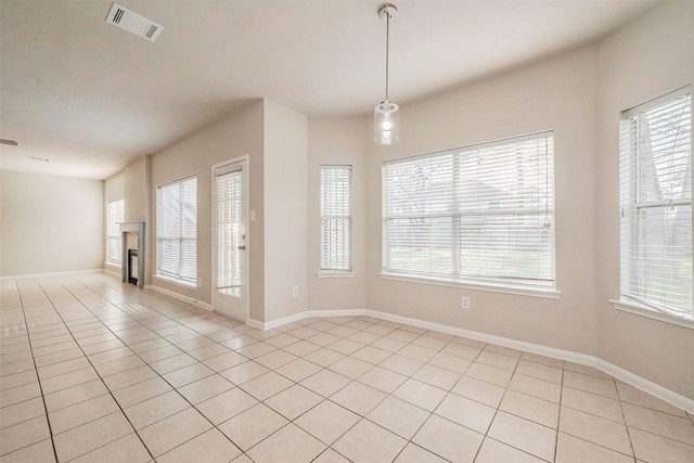 spare room featuring visible vents, baseboards, light tile patterned flooring, and a fireplace